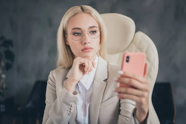 Photo of intelligent business lady sitting chair use browsing telephone hand touch chin loft office indoors.