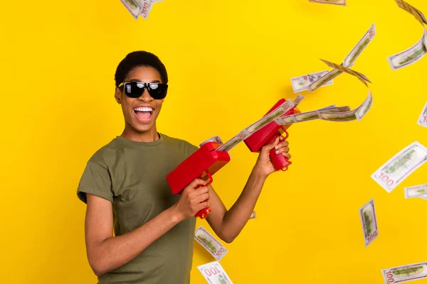 Photo of successful excited person shooting usd banknotes toothy smile isolated on yellow color background.