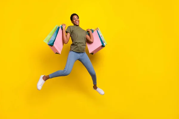 Full length portrait of crazy excited person jump hold packages isolated on yellow color background.