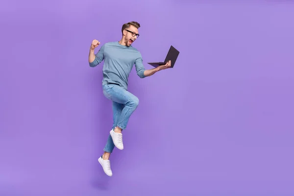忙しい幸運な男の写真を着てグレーのシャツ眼鏡ジャンプ高書き込み現代デバイス孤立紫色の背景 — ストック写真