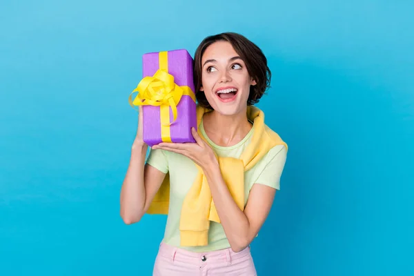 Photo of dreamy sweet woman wear green t-shirt guessing inside gift box isolated blue color background.