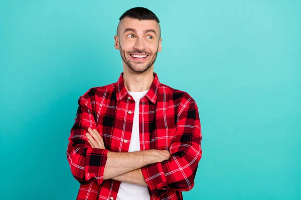 Photo of positive happy dreamy young man look empty space hands crossed isolated on teal color background.