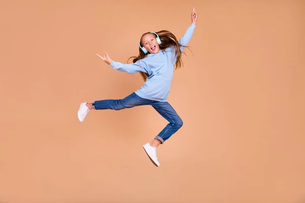 全身写真の不注意な小さな女の子ジャンプ指実証重い金属シンボル絶縁上ベージュ色背景 — ストック写真