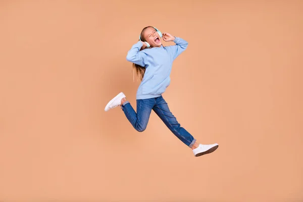 フルサイズの写真の満足女の子ジャンプ手タッチヘッドフォン悲鳴は楽しいです分離上ベージュ色背景 — ストック写真