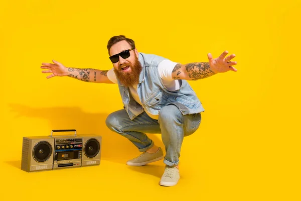 Photo of funny cool guy dressed denim vest dark glasses enjoying songs boombox dancing isolated yellow color background.