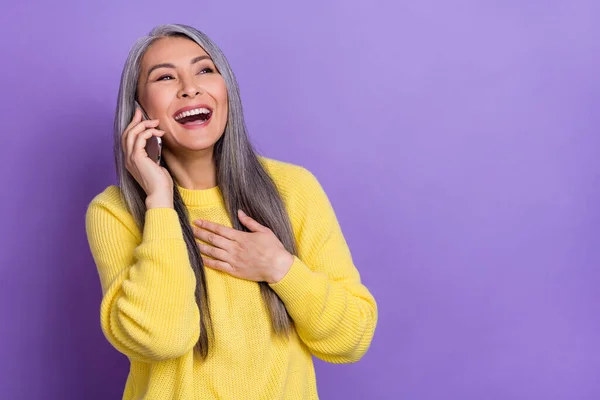 Photo of funky charming retired woman wear sweater talking modern device empty space isolated violet color background.