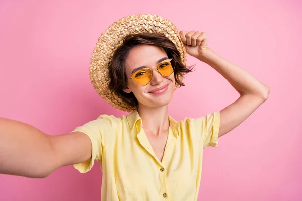 照片上的年轻姑娘开心而积极的笑着自拍了创纪录的视频旅行太阳帽与粉色背景隔离 — 图库照片