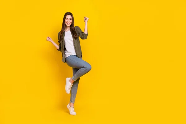 Full body photo of ecstatic overjoyed lady raise fists in victory win money in lottery giveaway isolated on yellow color background.