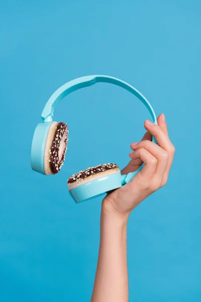 trend picture collage of human arm holding innovative headset with donut cookie muffs isolated blue color background.