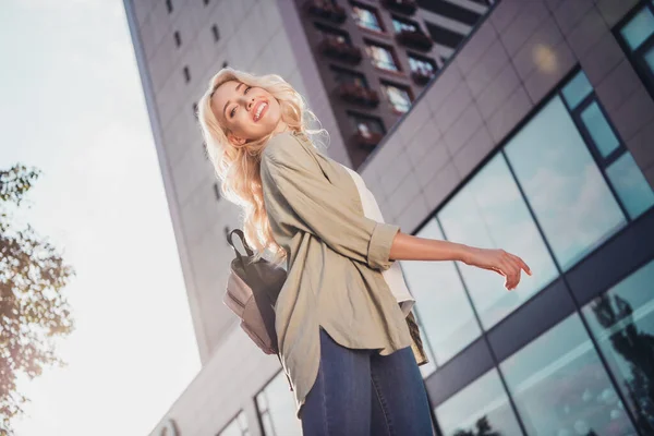 Profile side view portrait of attractive blond cheerful girl strolling dancing having fun sun shine in town outdoors.