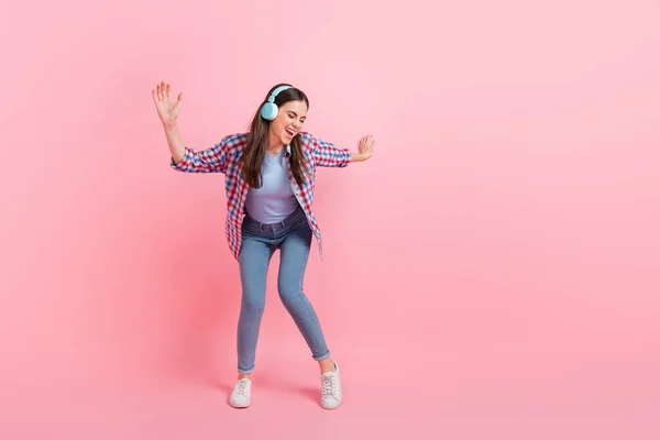 Full size image of overjoyed energetic dancing girl wear wireless headset isolated on pink color background.