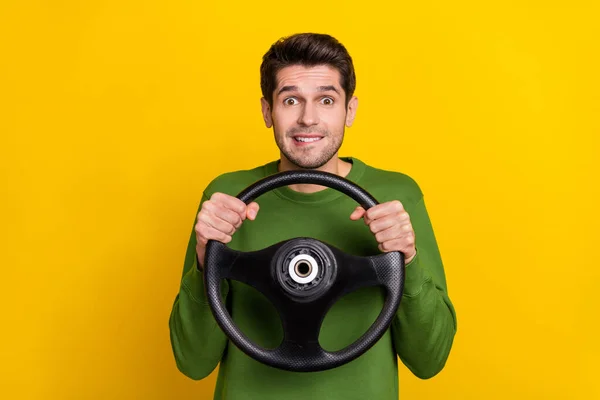 Portrait of attractive nervous worried guy holding steering wheel riding isolated over bright yellow color background.