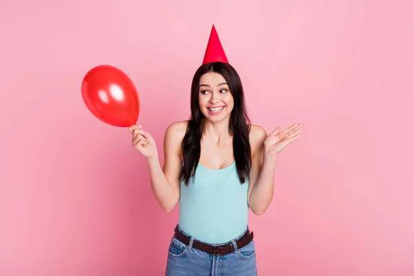 Photo of funny millennial birthday lady look balloon shrug shoulders wear hat blue top isolated on pink background.