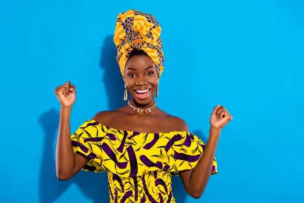 Photo of astonished cheerful dark skin person fists up open mouth shout yes isolated on blue color background.