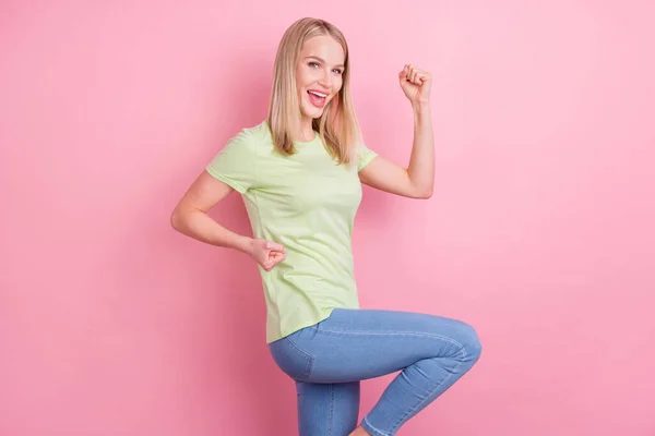 明るいクレイジー面白い女性の写真を上げる拳はピンクの背景に隔離された勝利の服緑のTシャツを祝う — ストック写真