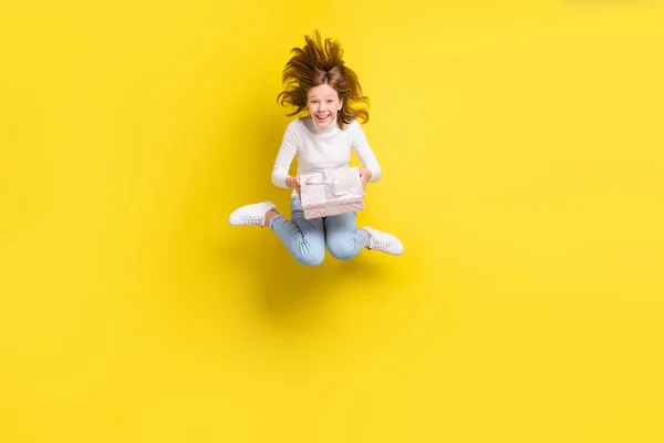 フルサイズ写真の幸せな素敵な若いブルネット小さな女の子ジャンプアップ良い気分ホールド現在のフライ髪絶縁で黄色の色の背景 — ストック写真