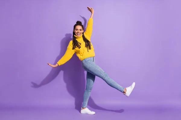 全长照片乐观漂亮的黑发女孩跳舞穿毛衣牛仔裤运动鞋与紫色背景隔离 — 图库照片