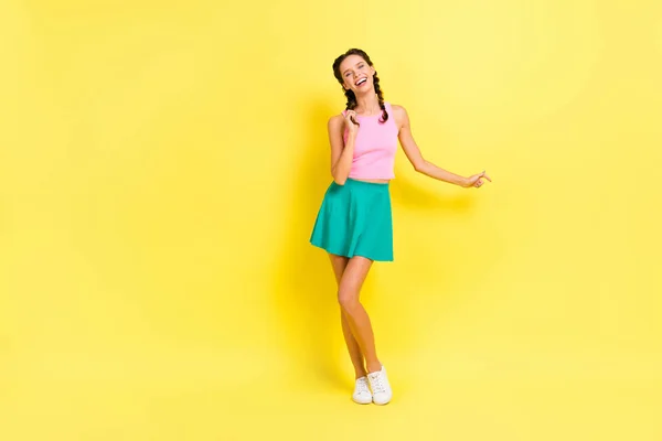 楽観的な素敵なブルネットの女性のダンスのフルサイズの写真は 鮮やかな黄色の色の背景に隔離されたピンクトップブルーのスカートを着用 — ストック写真