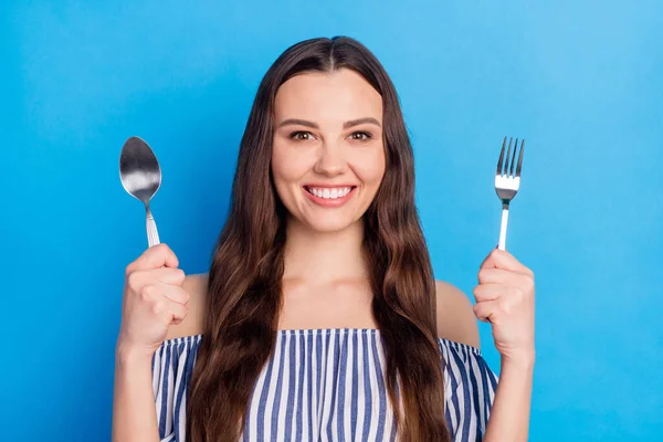 Photo portrait woman hungry before breakfast with fork knife smiling isolated bright blue color background.