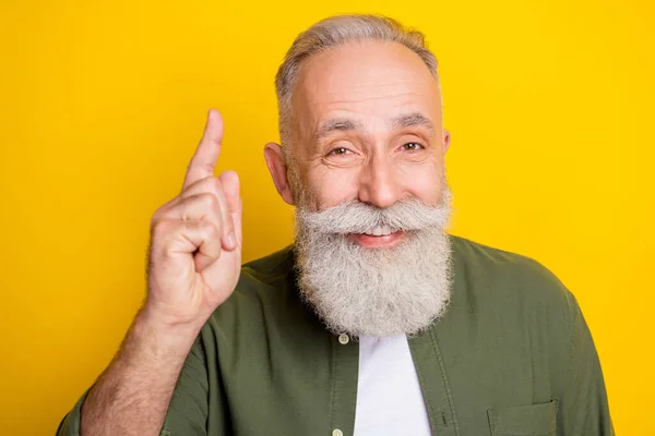 Photo portrait of elder man pointing finger up giving advice recommending isolated bright yellow color background.