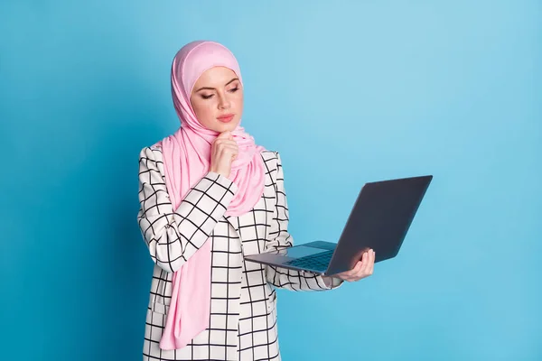若い真面目なイスラム教徒の少女の写真深い考え読み取りコンピュータは 青の色の背景に孤立ヒジャーブを身に着けている — ストック写真