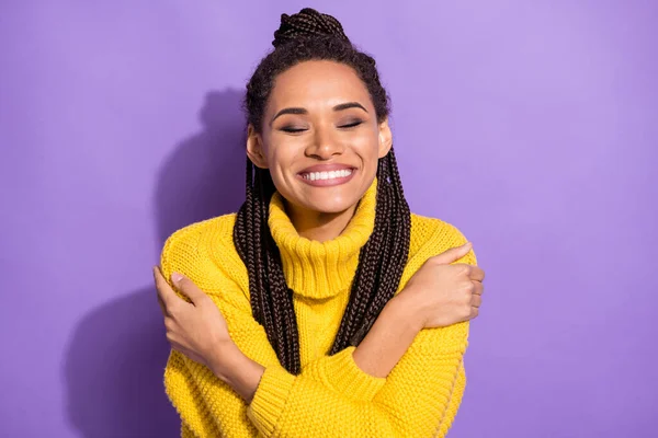 Photo portrait of adorable girl hugging self smiling isolated on vivid violet colored background.