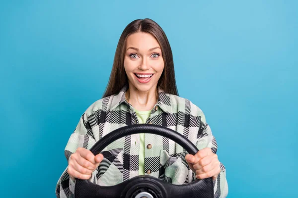 照片上的年轻姑娘开心的笑着坐汽车方向盘在蓝色的背景上被隔离了 — 图库照片