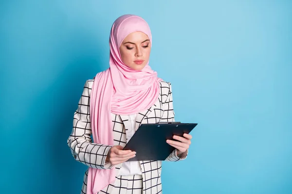 若い深刻なアラビア人の女性の写真は クリップボードのチェックプランは 青の色の背景の上に隔離ヒジャーブを着用見て — ストック写真