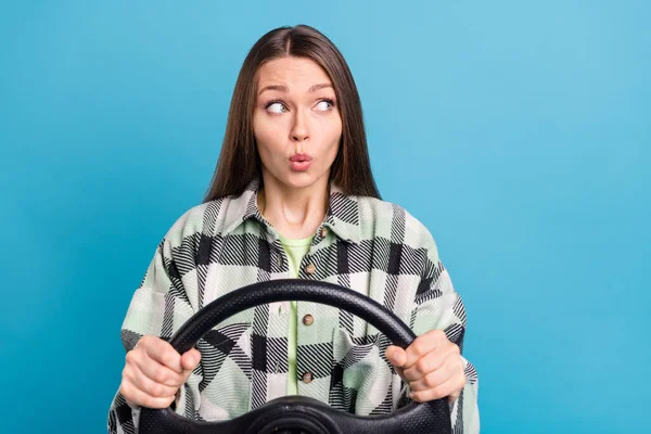 Photo of young girl amazed shocked look empty space ride auto steering-wheel vehicle isolated over blue color background.