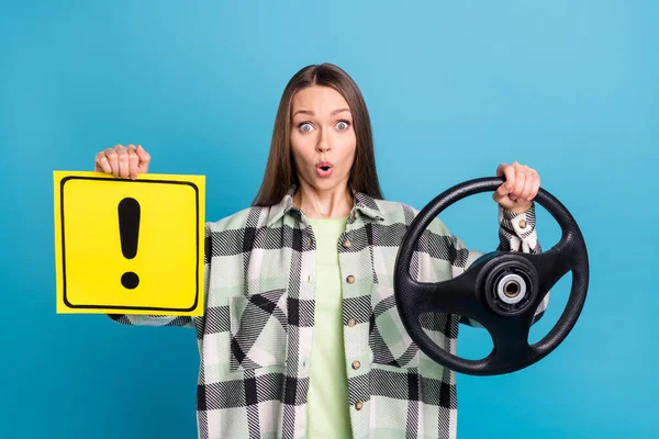Photo of young shocked woman hold steering wheel danger sign amazed isolated on blue color background.