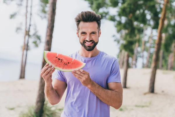 Portrait of satisfied cheerful person hold piece watermelon toothy smile enjoy pastime outside.