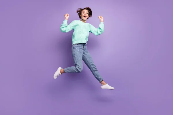 Full length body size photo of cheerful happy model jumping high gesturing like winner isolated pastel violet color background.