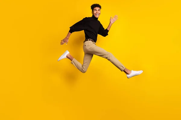かなり魅力的な黒い肌の男の写真黒セーターのアイウェアを実行している高速ジャンプ孤立黄色の背景 — ストック写真