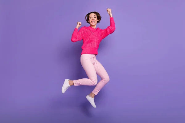 フルボディ写真の若い女の子幸せ祝い勝利ジャンプアップ着用パンツ拳手孤立以上紫の色の背景 — ストック写真