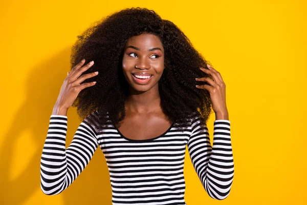 Photo portrait of young model smiling cheerfully touching hair in casual clothes looking copyspace isolated bright yellow color background.