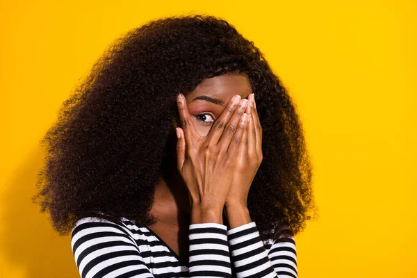 Photo portrait of young woman covering face with hands playing peekaboo isolated bright yellow color background.
