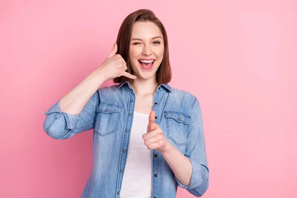 Photo portrait of girl smiling asking to call her showing finger at you isolated pastel pink color background.