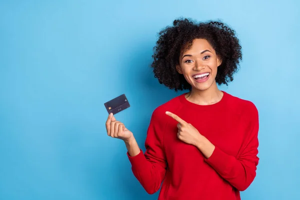 Photo of pretty excited lady dressed red pullover pointing credit card empty space isolated blue color background.