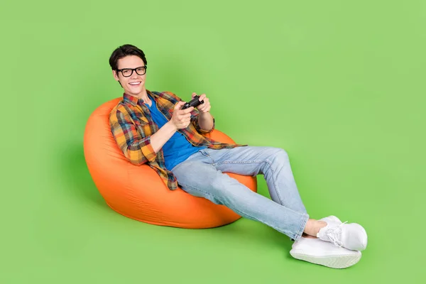 Photo of gamer guy hold joystick play video game wear specs checkered shirt isolated green color background.