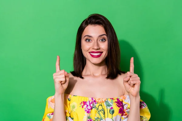 Photo of cheerful lovely lady toothy smile direct fingers up empty space isolated on green color background.