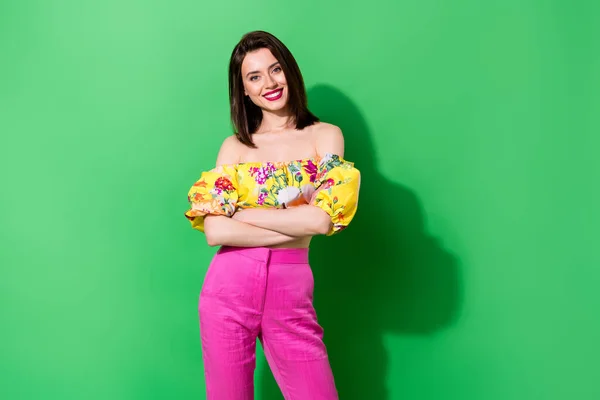 Photo of lovely cute person crossed arms beaming smile empty space isolated on green color background.