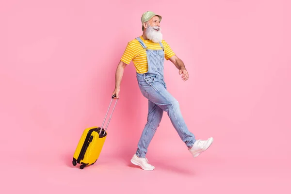 Full length body size view of attractive cheerful man carrying bag going abroad isolated over pink pastel color background.