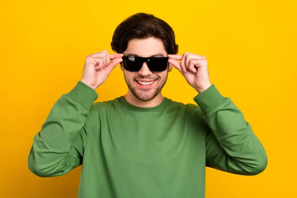 若い幸せなクールな肯定的な男の写真は黄色の色の背景に隔離されたサングラス緑のセーターの笑顔を着用 — ストック写真