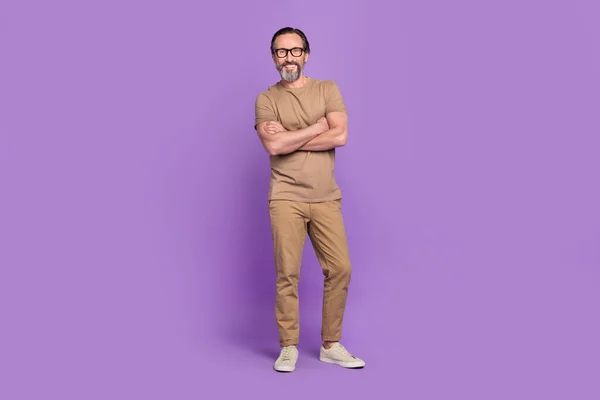Full length photo of aged man crossed hands wear modern outfit isolated over violet color background.