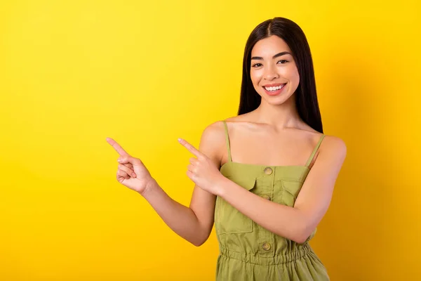 Portrait of cheerful adorable filipino girl toothy smile direct fingers empty space blank isolated on yellow color background.