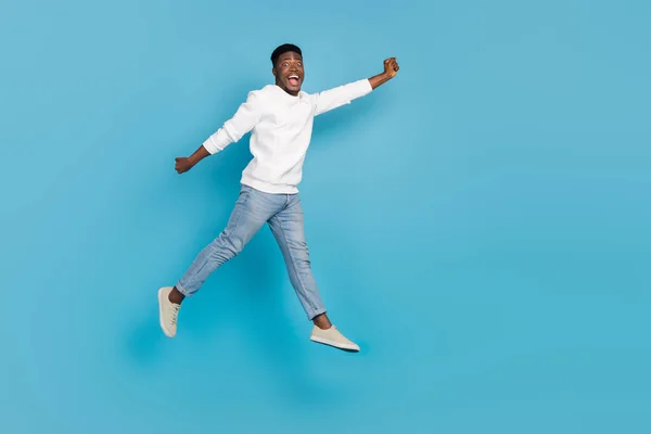 Full length photo of astonished satisfied person jump fly raise hand isolated on blue color background.