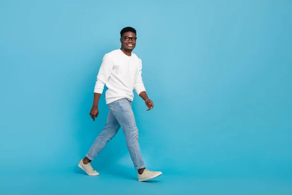 Full body profile photo of positive cheerful person walking toothy smile isolated on blue color background.