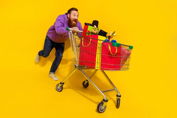 Full size photo of crazy carefree person push trolley hurry fast run low price isolated on yellow color background.