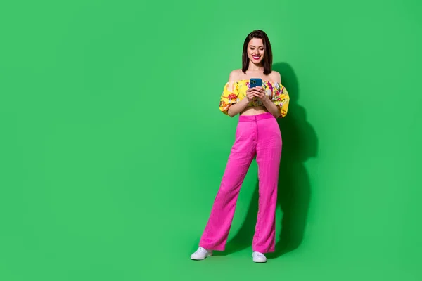 Full length photo of adorable sexy girl dressed off shoulders top writing modern device isolated green color background.