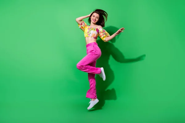 Full length photo of sweet cute girl dressed off shoulders top jumping high smiling isolated green color background.